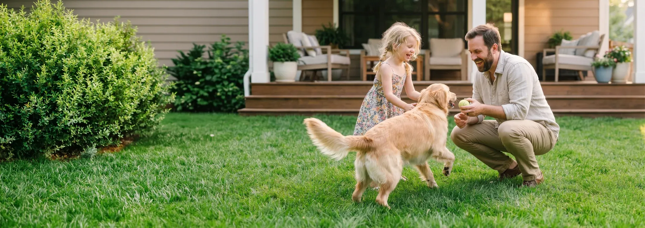 Dad and daughter playing outside with dog